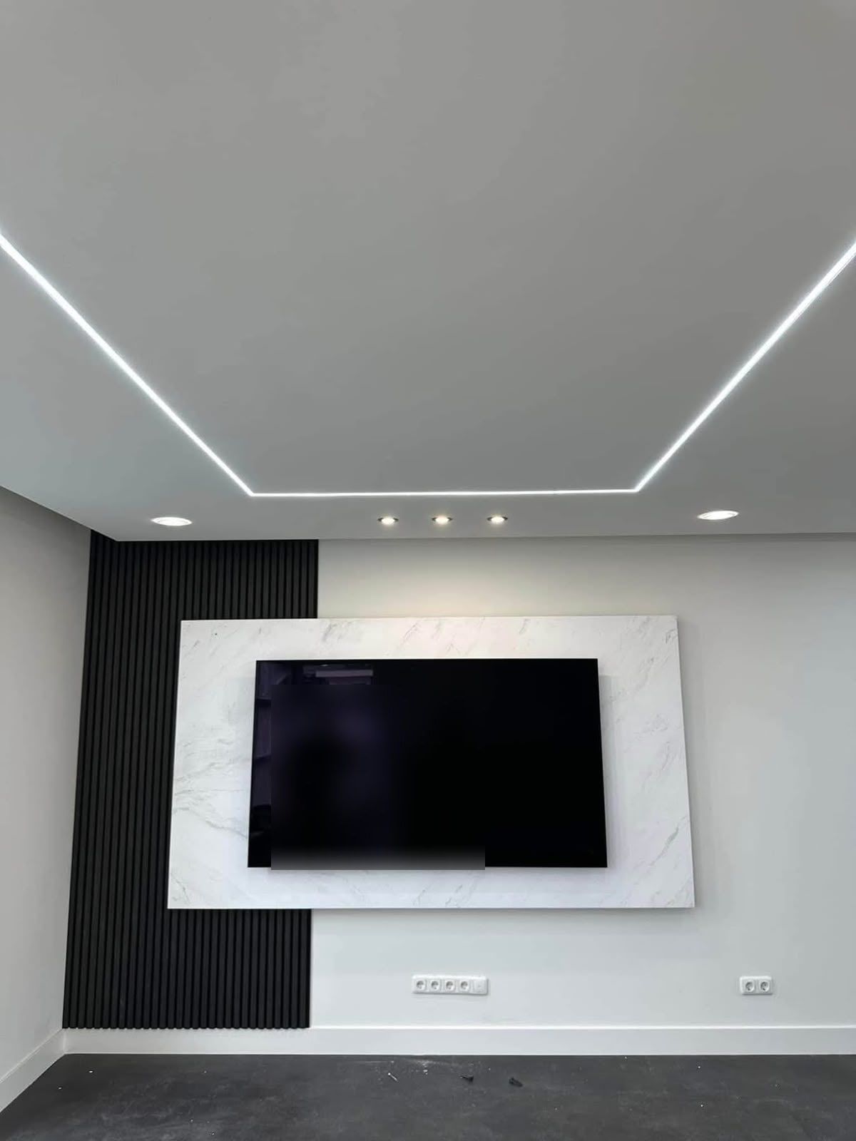 Strak gestuct plafond met LED-lijnen en een tv-wand in marmerlook